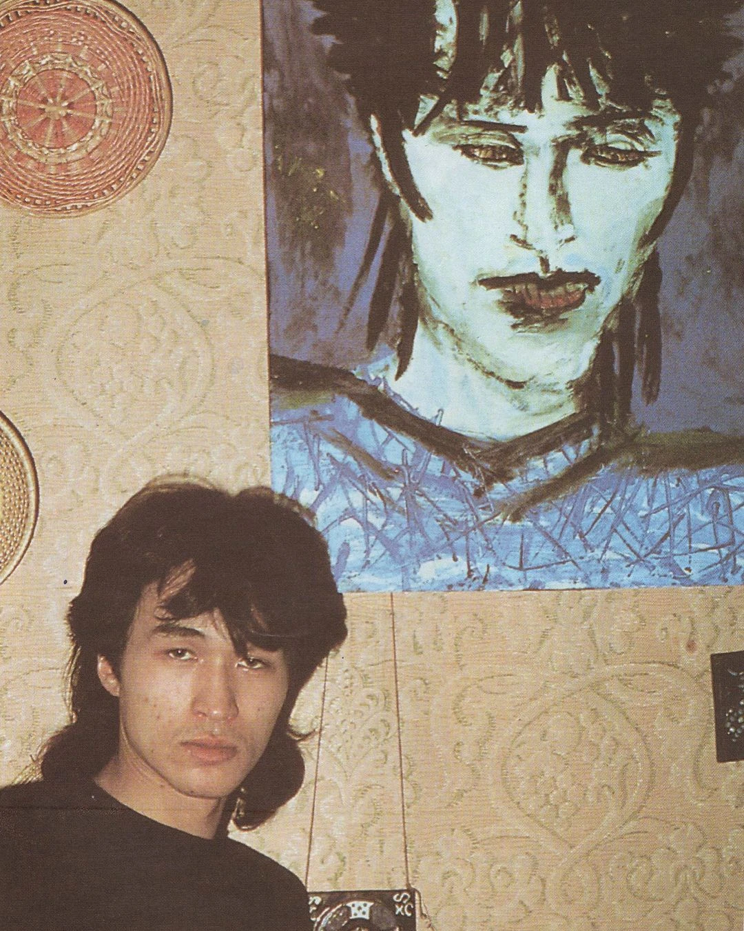 Виктор Цой на фоне своего портрета кисти Тимура Новикова. Вторая половина 1980-х.<br> Фото: Тимур Новиков / скан из книги «Red Wave Presents: A Viktor Tsoi Photobook, ” 1993 / @pinakotheca / Twitter